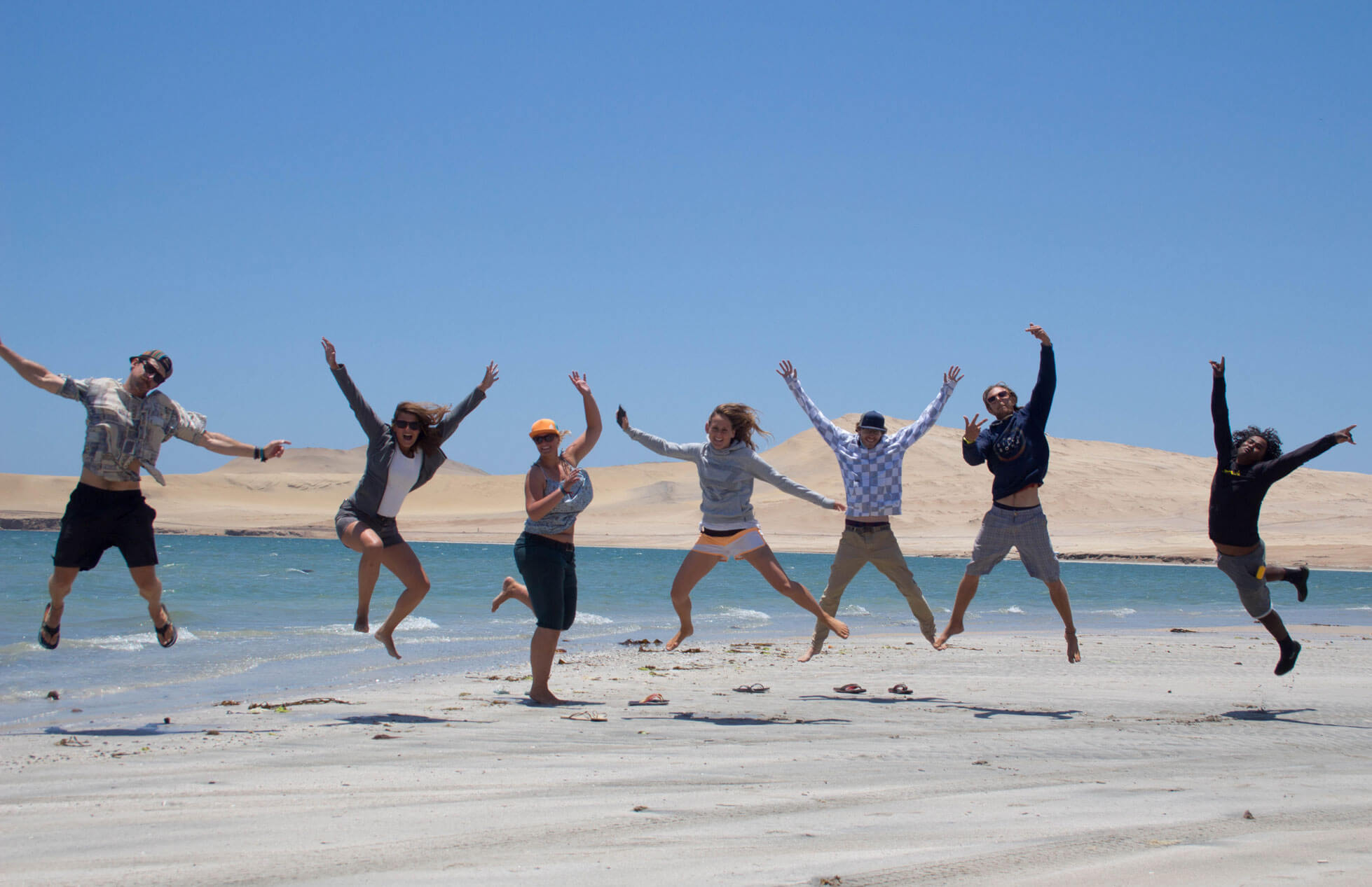 group of people jumping on a beach during a tour in paracas